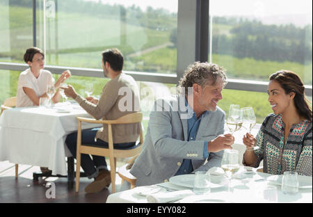 Couple toasting with wine glasses in sunny winery salle à manger Banque D'Images