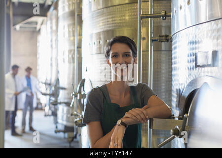 Portrait smiling vigneron à tva en acier inoxydable dans la cave de vinification Banque D'Images