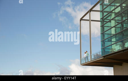 Hommes debout sur le balcon de verre bump contre ciel bleu Banque D'Images