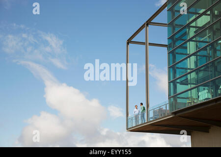 Hommes parler sur balcon de verre bump contre ciel bleu Banque D'Images