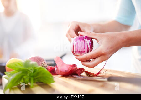 Woman peeling oignon rouge dans la cuisine Banque D'Images