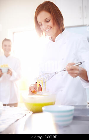 Smiling chef baking in kitchen Banque D'Images