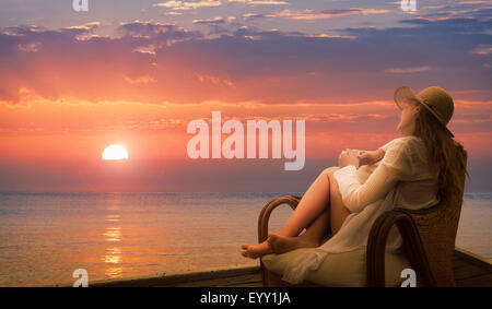 Caucasian woman admiring coucher du soleil sur la plage Banque D'Images
