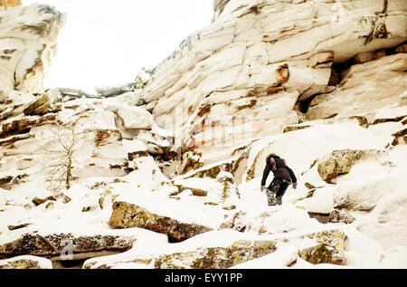 Caucasian hiker escalade rochers enneigés Banque D'Images