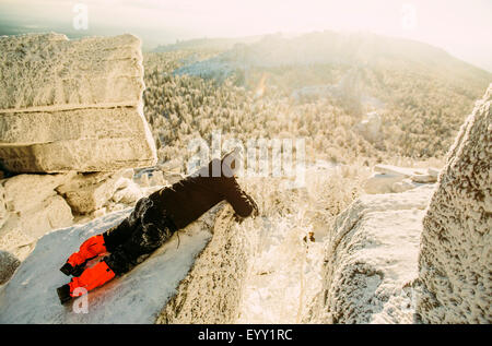 Caucasian hiker portant sur des formations rocheuses enneigées Banque D'Images