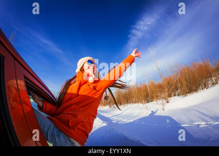 Caucasian woman leaning out car window in snowy field Banque D'Images