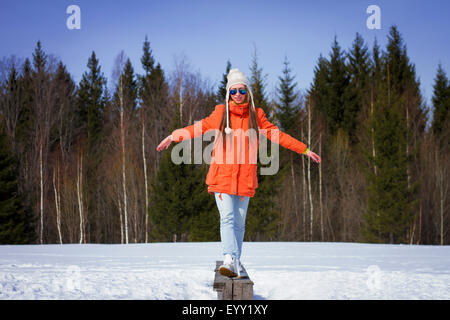 Caucasian woman balancing sur banc en bois in snowy field Banque D'Images