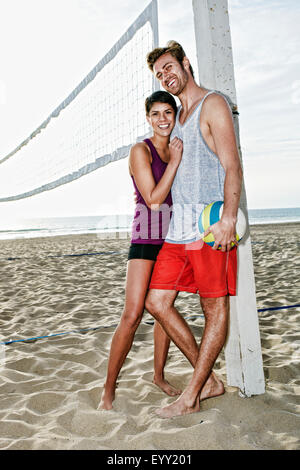 Couple hugging près de filet de volley-ball sur plage Banque D'Images