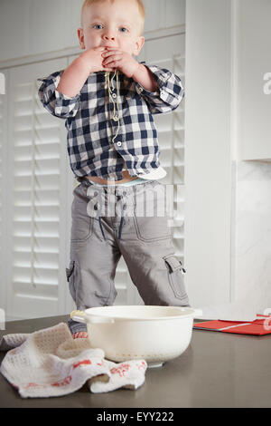 Caucasian boy standing on table jouant avec la nourriture Banque D'Images