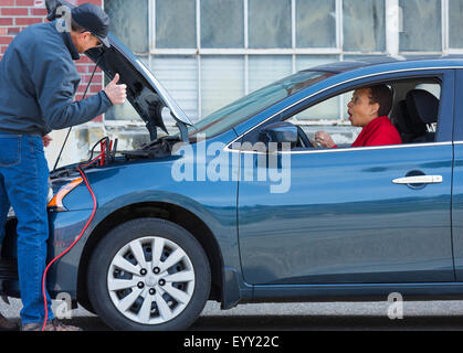 Batterie pour mécanicien jumping woman in car Banque D'Images