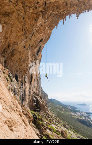 Caucasian climber hanging from cable sur mur de pierre Banque D'Images