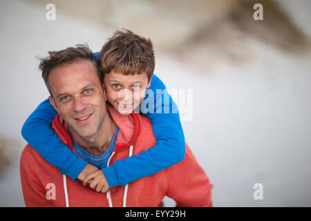 Woman carrying son piggyback outdoors Banque D'Images