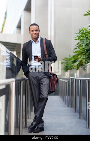 Black businessman using cell phone outside building Banque D'Images