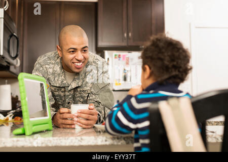 Mixed Race soldat père et fils de manger dans la cuisine Banque D'Images