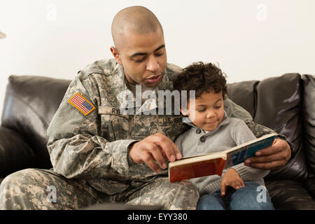 Mixed Race soldat lecture livre à fils sur canapé Banque D'Images