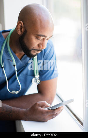 Infirmière Black téléphone cellulaire à l'aide de fenêtre près de Banque D'Images