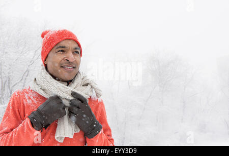 Homme noir portant des gants et écharpe dans la neige Banque D'Images
