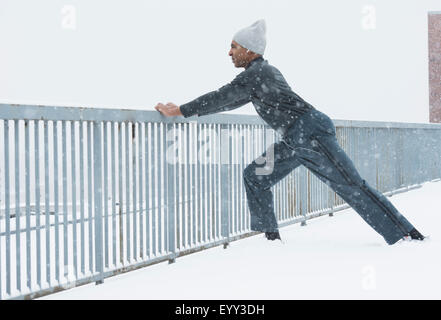 Black runner stretching in snow Banque D'Images