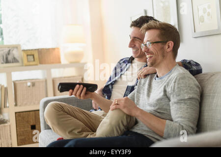 Caucasian couple gay, regarder la télévision sur le canapé Banque D'Images