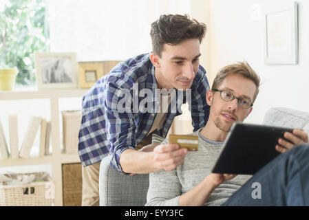 Young gay couple shopping online on digital tablet Banque D'Images