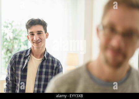 Young gay couple smiling in home Banque D'Images