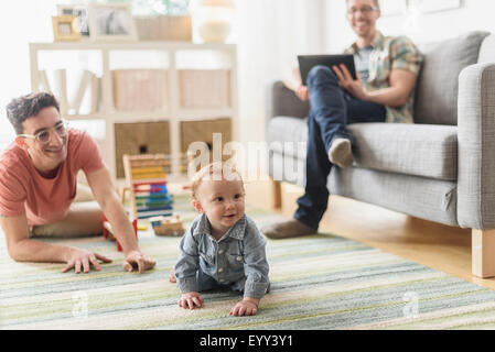 Caucasian gay fathers and baby relaxing in living room Banque D'Images