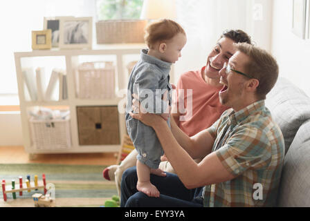 Les pères gays caucasienne et bébé jouant dans la salle de séjour Banque D'Images