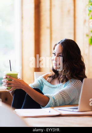 Chinese woman drinking smoothie in cafe Banque D'Images