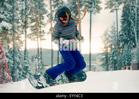 Caucasian girl riding snowboard dans la neige Banque D'Images