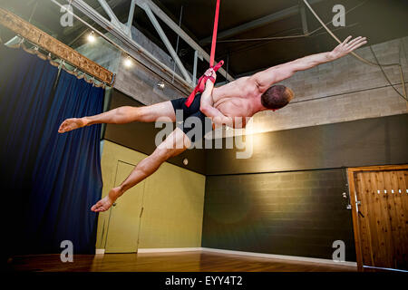 Caucasian acrobat suspendu à des cordes en studio Banque D'Images