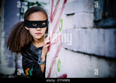 Mixed Race girl en masque d'oeil autour du coin Banque D'Images