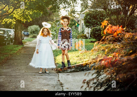 Soeurs portant un costume d'Halloween sur le trottoir Banque D'Images