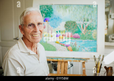 Caucasian artist smiling avec la peinture en studio Banque D'Images