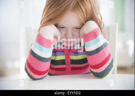 Caucasian girl crying at table Banque D'Images