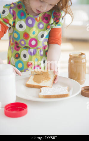 Caucasian girl répandre le beurre d'arachide sur du pain Banque D'Images