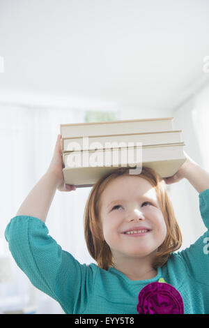 Caucasian girl balancing books on head Banque D'Images