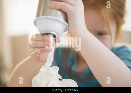 Caucasian girl spraying crème fouettée Banque D'Images