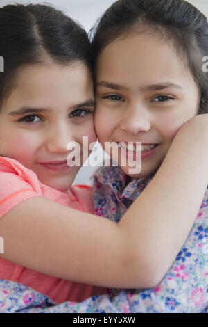 Close up of Hispanic sisters hugging Banque D'Images