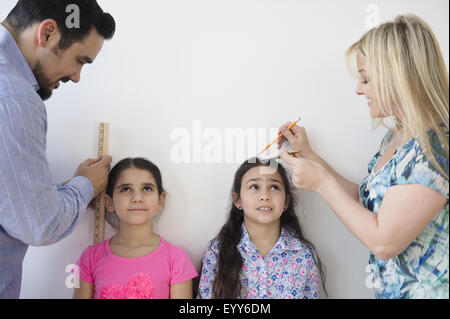 Les parents de race blanche mesure de la hauteur des filles sur le mur Banque D'Images