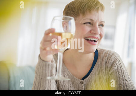 Caucasian woman drinking glass of wine in living room Banque D'Images