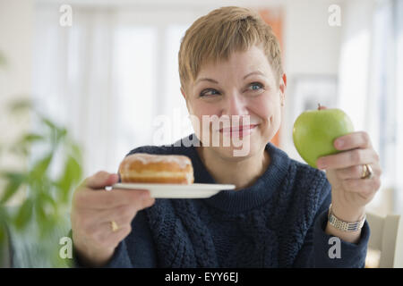 Caucasian woman choisir entre donut et Apple Banque D'Images