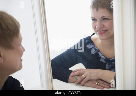 Caucasian woman admiring Herself in mirror Banque D'Images