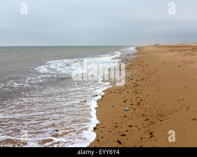 Longue plage de sable avec douces vagues venant à terre sur une journée terne le littoral de Norfolk en Angleterre Banque D'Images