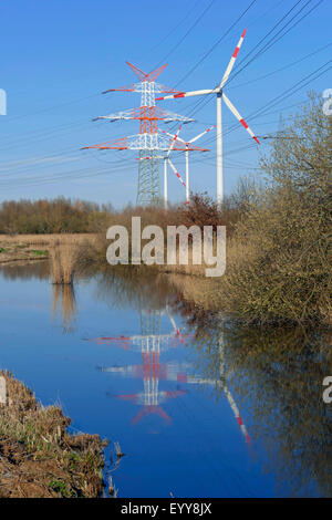 Poteaux d'électricité et la mise en miroir les roues du vent dans un fossé, l'Allemagne, elle Werderland, Brême Banque D'Images