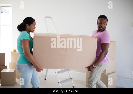 Couple carrying cardboard box in new home Banque D'Images