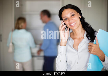 Realtor talking on cell phone with couple in new home Banque D'Images