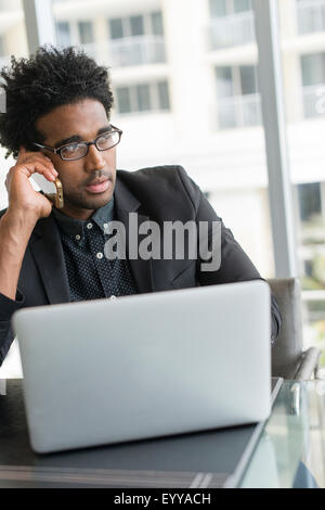 Hispanic businessman talking on cell phone in office Banque D'Images