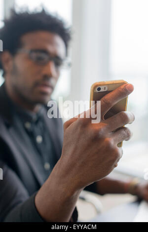 Hispanic businessman using cell phone in office Banque D'Images