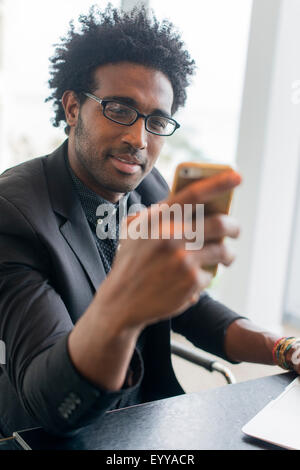 Hispanic businessman using cell phone in office Banque D'Images