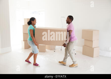 Couple carrying cardboard box in new home Banque D'Images